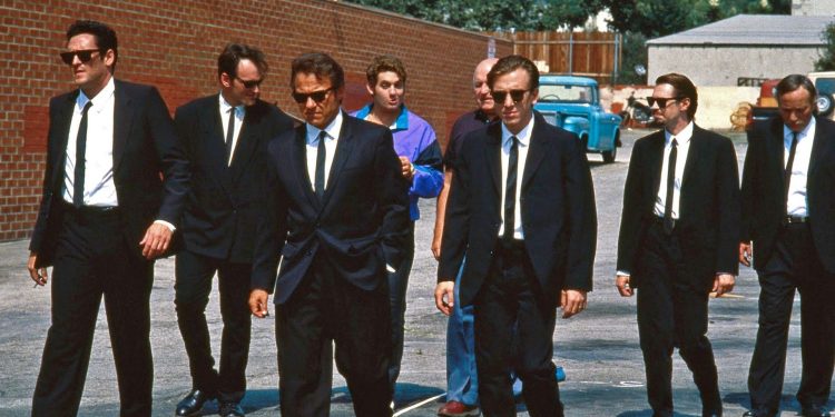Michael Madsen (Blonde), Harvey Keitel (White), e Steve Buscemi (Pink), Quentin Tarantino (Brown), Edward Bunker (Blue), Cabot (Lawrence Tierney), e Nice Guy Eddie (Chris Penn) em uma famosa foto oficial de Cães de Aluguel.